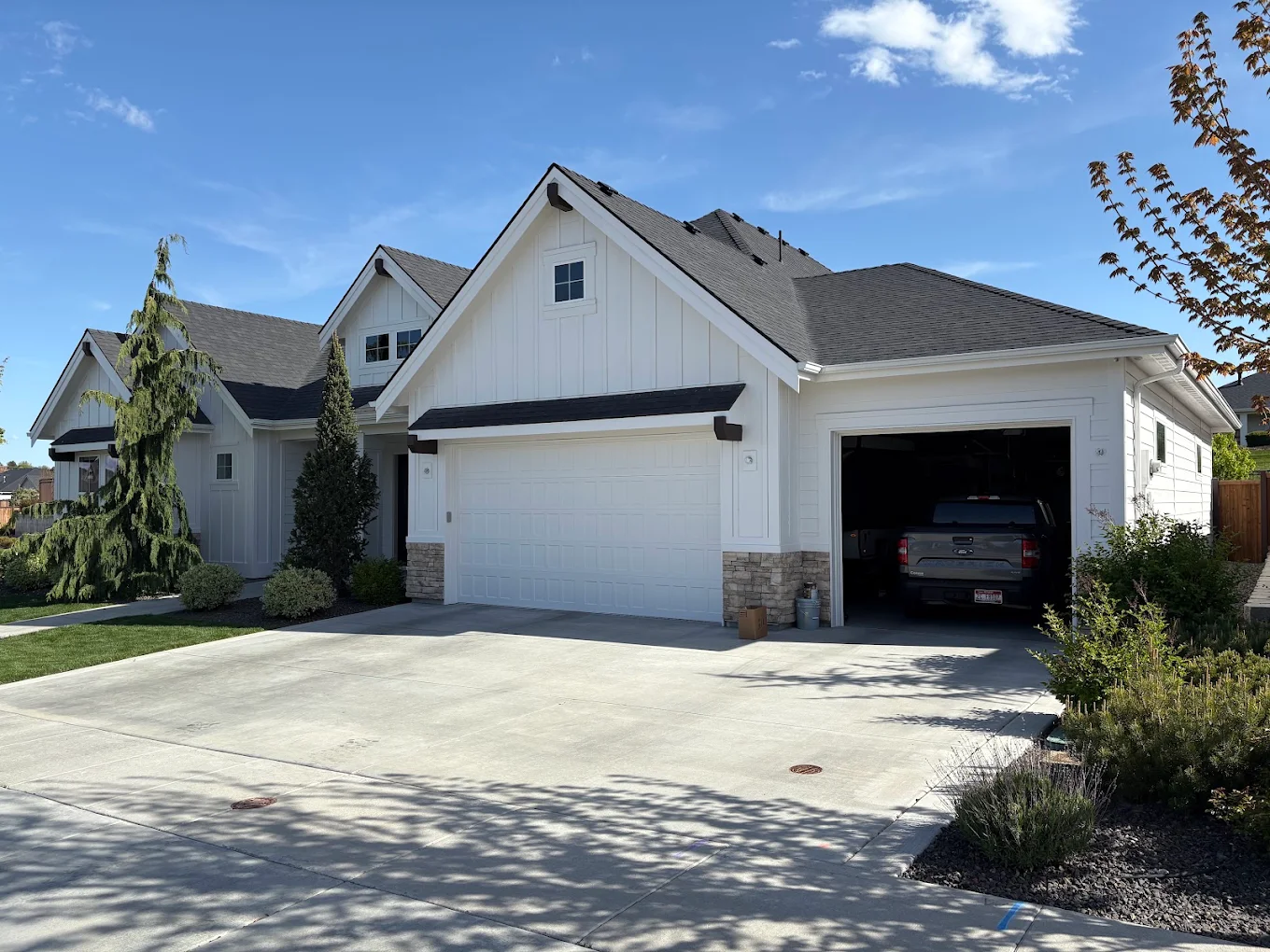 Residential exterior painting of a white farmhouse with three-car garage in Idaho